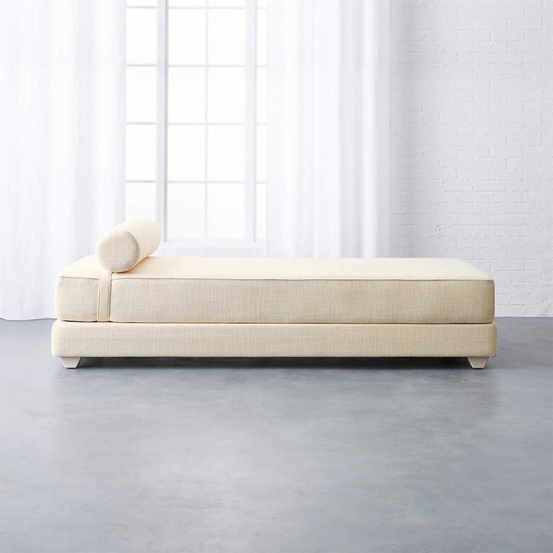 A white couch featuring wooden legs and a matching white cushion, elegantly designed for modern interiors