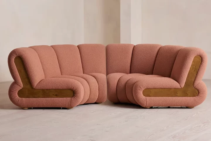 A pink couch featuring a wooden frame and arm, elegantly designed for a stylish living space
