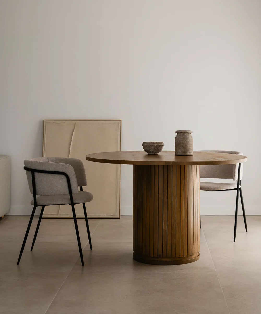 A round wooden dining table with a sturdy wooden base, showcasing a natural finish and elegant design