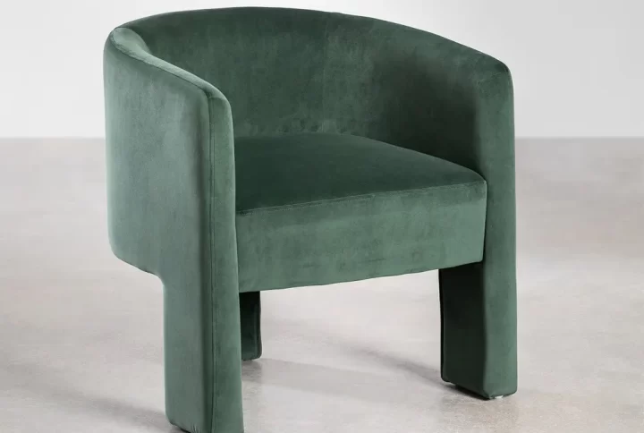 A green velvet Dining chair featuring a gracefully curved back, adding elegance to any interior space