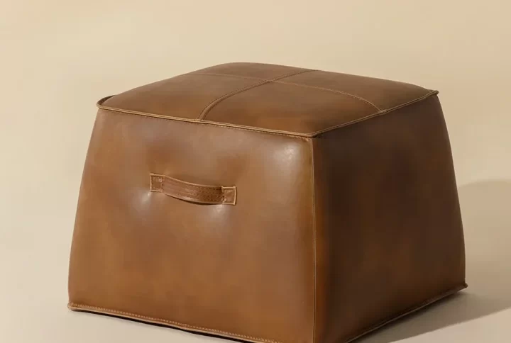 A square brown leather ottoman, showcasing a sleek and modern design, perfect for any living space