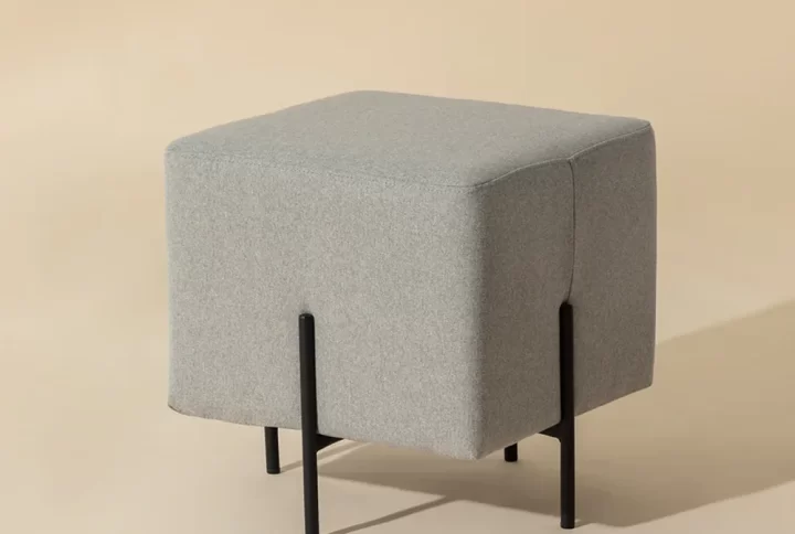 A small square stool featuring sleek black legs, designed for compact spaces and modern aesthetics