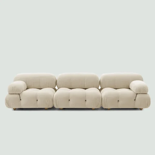 A modern, puffy white sofa with a tufted design and short wooden legs.