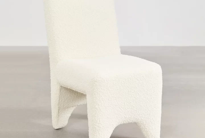 A simple chair and table positioned in front of a plain wall, creating a minimalist setting