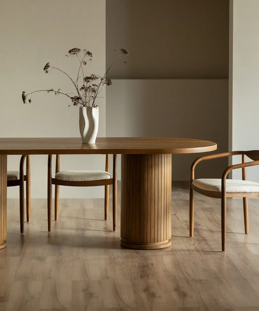 A wooden dining table with four matching chairs and a vase placed elegantly on top