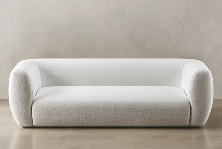 A white couch positioned on a sleek concrete floor, showcasing a modern and minimalist interior design