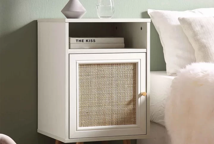 Frances Bedside Table with woven rattan cabinet door and washed white finish, styled in a rustic bedroom