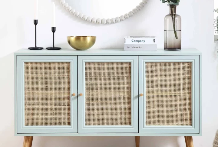 A white sideboard featuring rattan doors, complemented by a stylish lamp on top, enhancing the room's decor