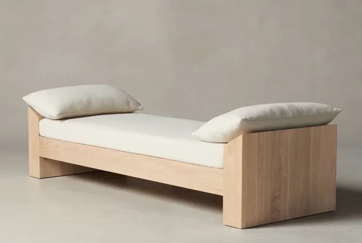 A wooden daybed adorned with colorful pillows, inviting relaxation in a serene outdoor setting