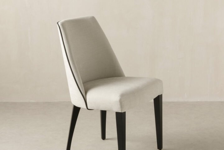 Arles Dining Chair with black trim, upholstered seat, and wooden legs in a modern dining room.