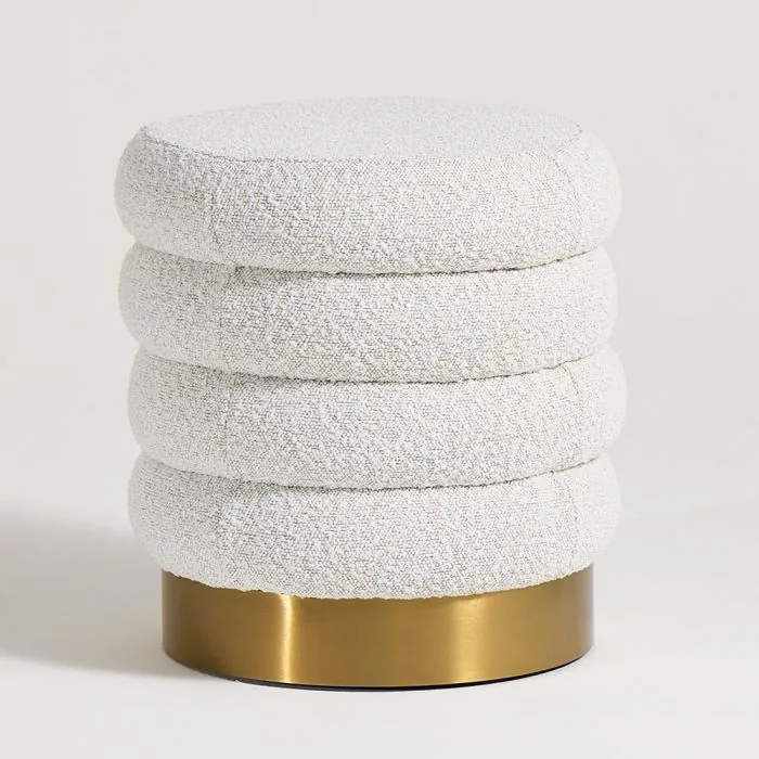 Boucle pouf with stacked rounded cushions and brass base in a modern sculptural design.