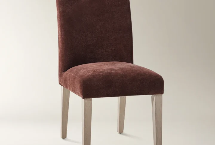 Modern burgundy upholstered dining chair with curved backrest and light wood legs.